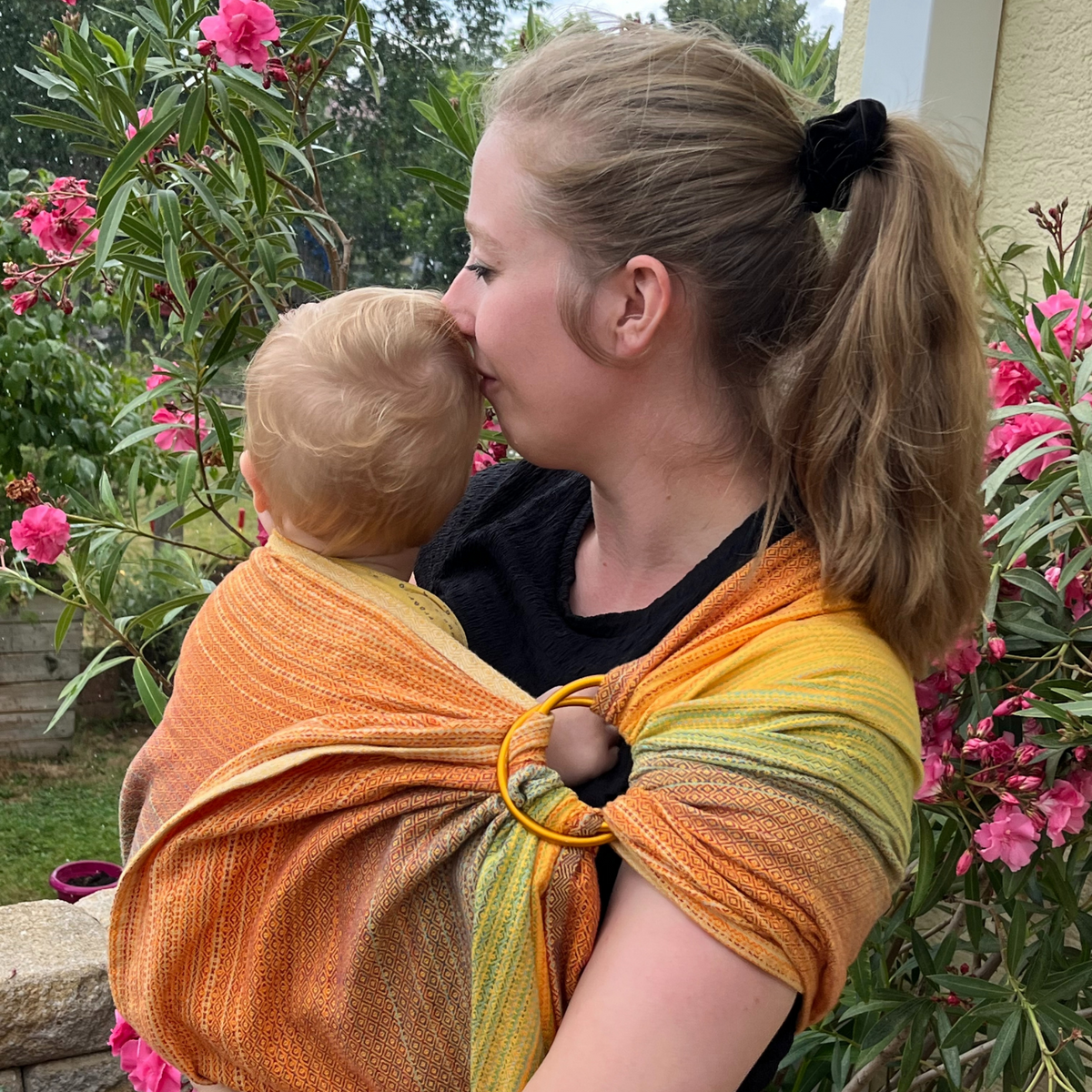 Girasol Ringsling Free Elf fusion d&#39;oro double weft Tragebild Mama und Baby vond er Seite vor einem Oleander mit rose Blüten
