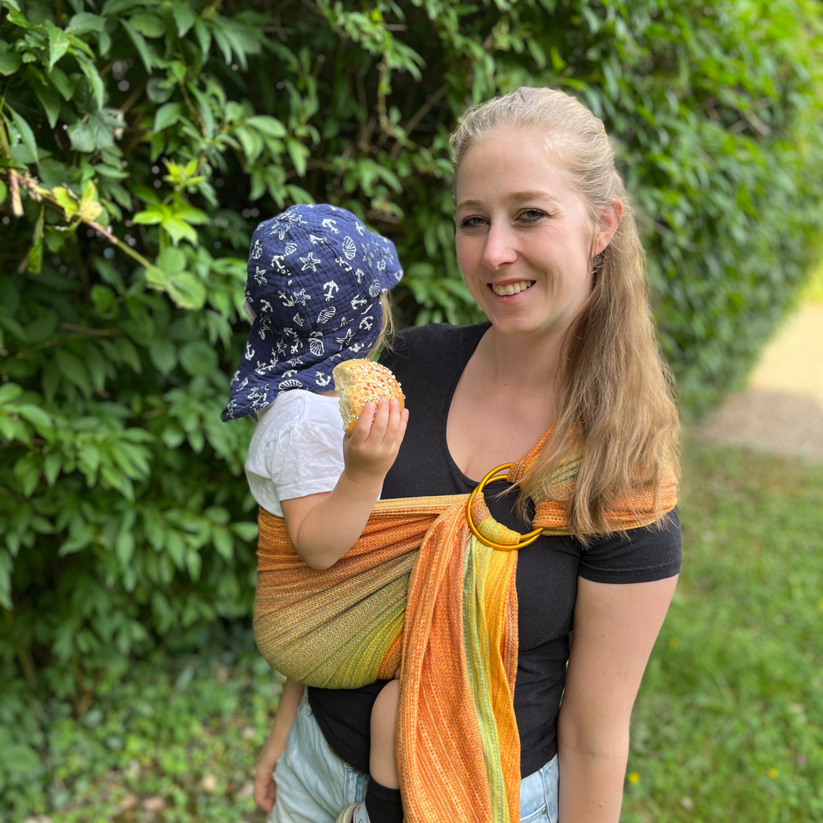Girasol Ringsling Free Elf fusion d&#39;oro double weft Tragebild mit Baby und Mama, das Baby isst dabei ein Brötchen